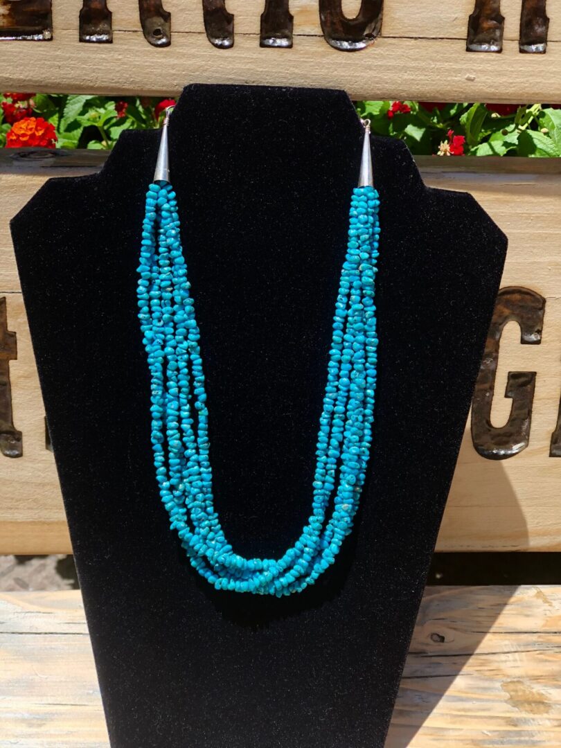 A turquoise beaded necklace on display on a mannequin.