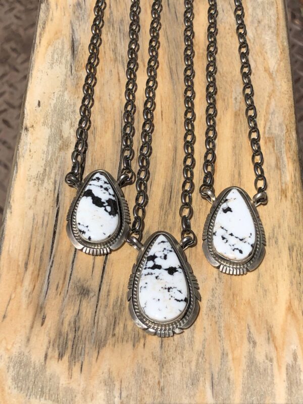 Three pendants with white and black stones on silver chains.