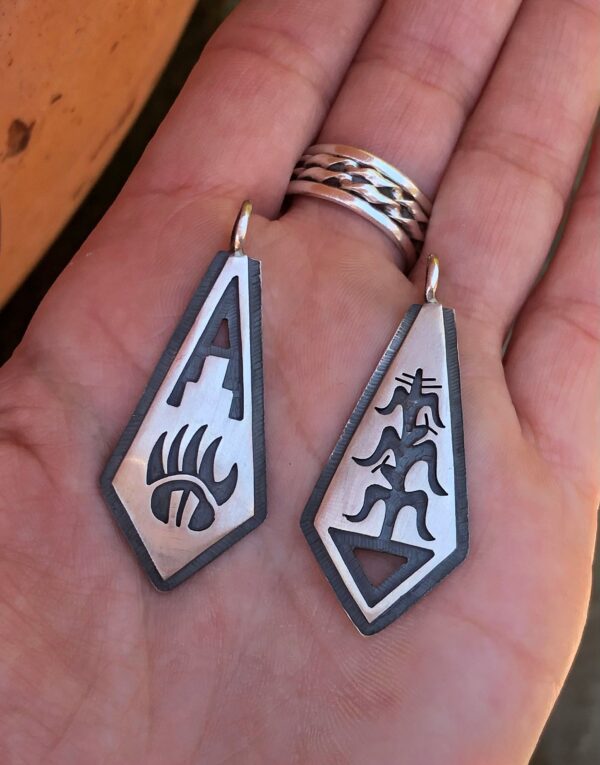 Two silver pendants with Native American designs.