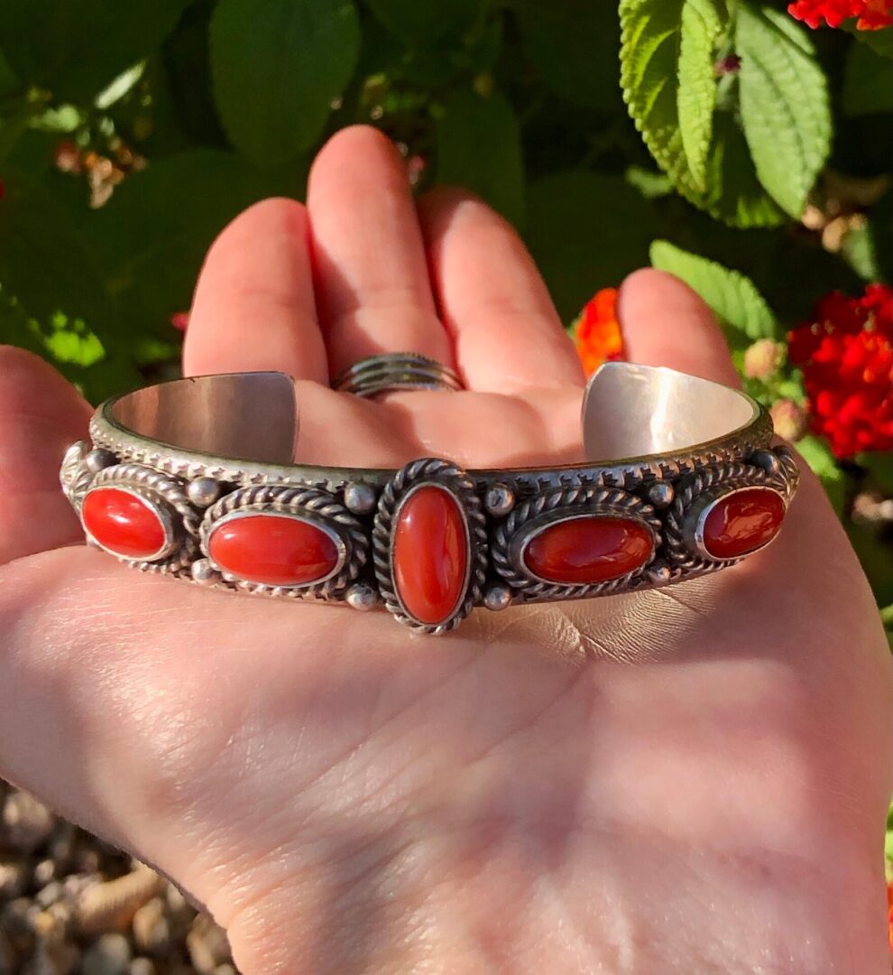 A silver bracelet with five oval red coral stones.