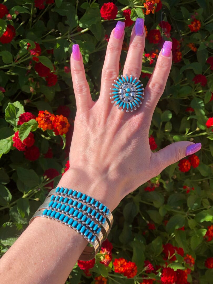 A hand wearing a turquoise and silver ring and bracelet.