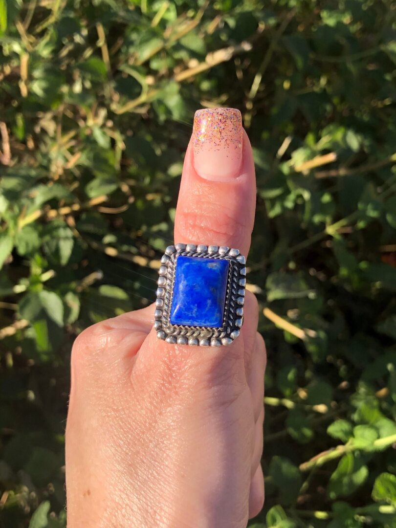 A person holding up a lapis stone ring.