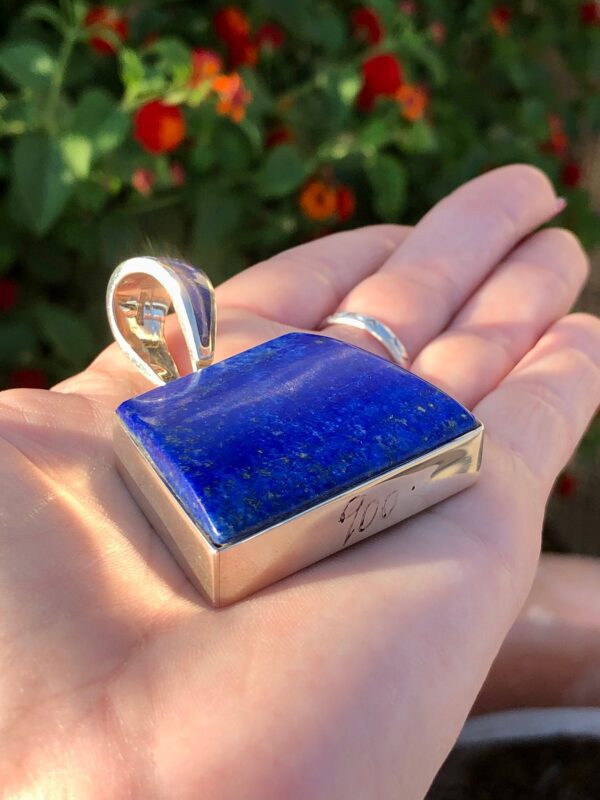 A hand holding a lapis lazuli pendant.