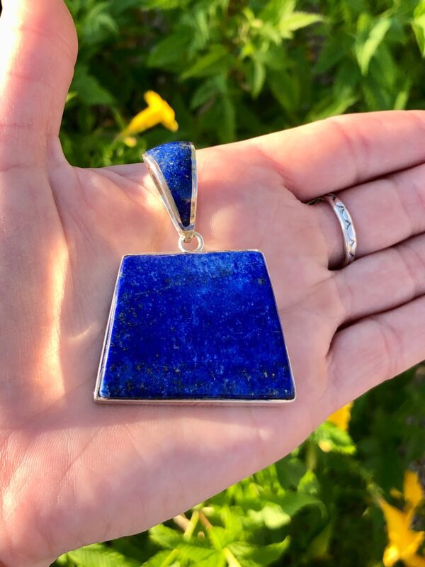 A hand holding a lapis lazuli pendant.