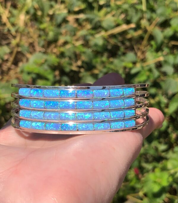 A person is holding a blue opal cuff bracelet.