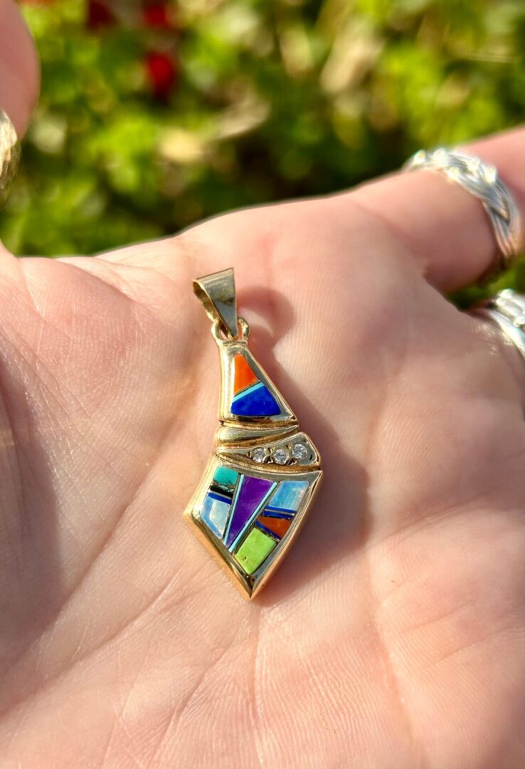 A person holding a colorful pendant in their hand.