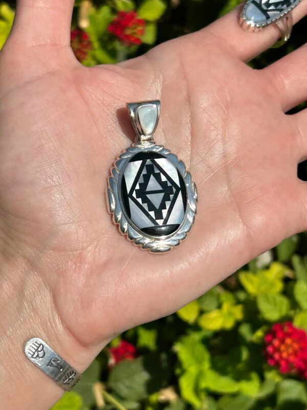 A silver pendant with black and white inlay.