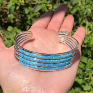A person holding a blue opal cuff bracelet.