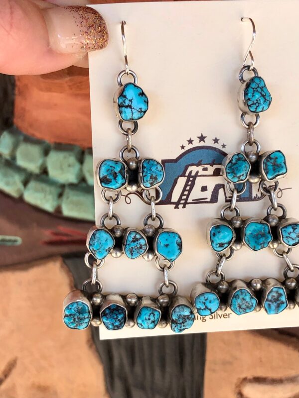 A pair of silver earrings with turquoise stones.