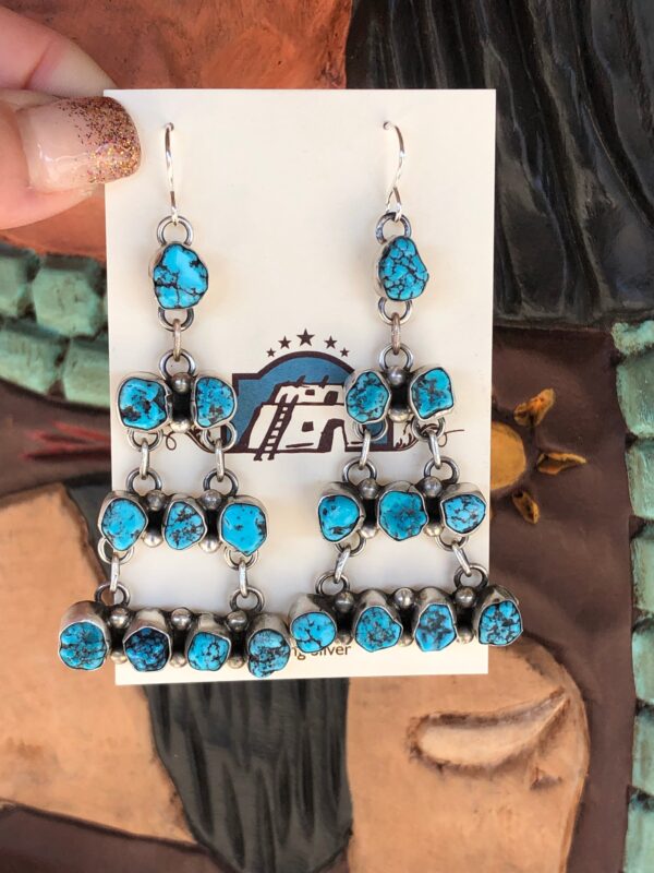 A pair of silver earrings with blue turquoise stones.