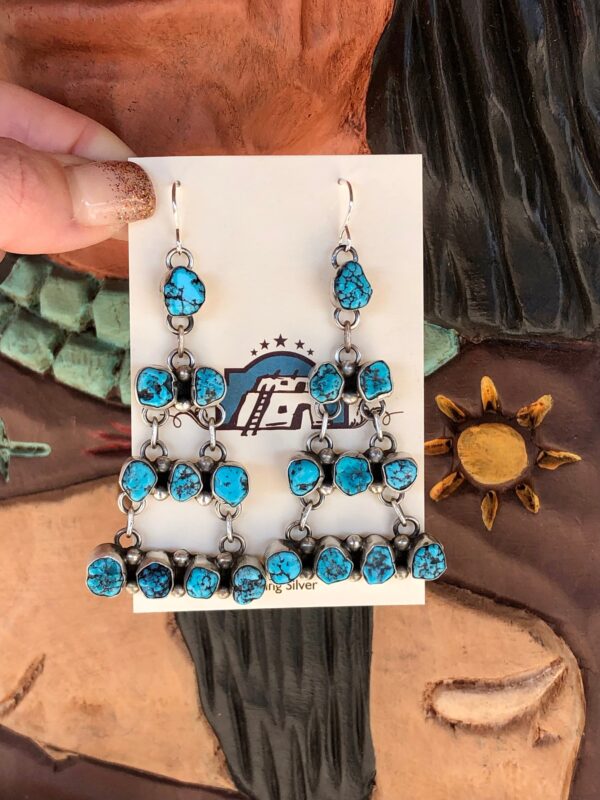 A pair of silver earrings with blue turquoise stones.