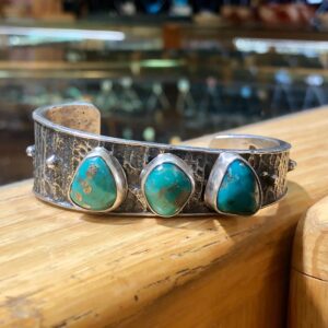 A silver cuff bracelet with turquoise stones.