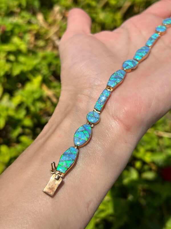 A person is holding a blue opal bracelet.