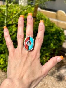 A woman's hand holding a ring with a colorful design.