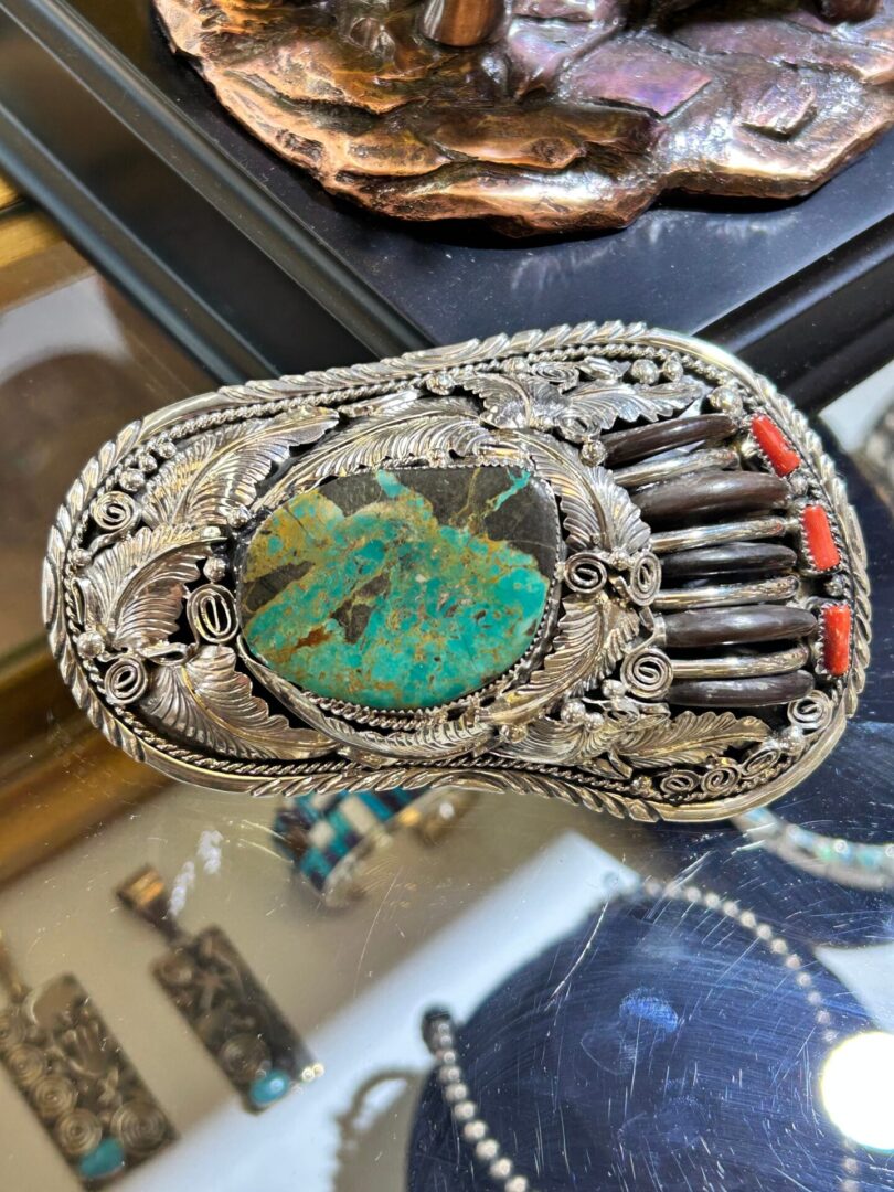 A silver and turquoise brooch with a turquoise stone.