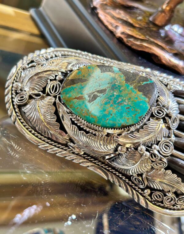 A silver hair comb with a turquoise stone.