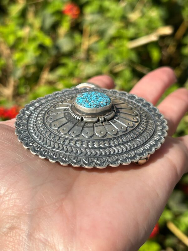 A silver and turquoise brooch with a turquoise stone.
