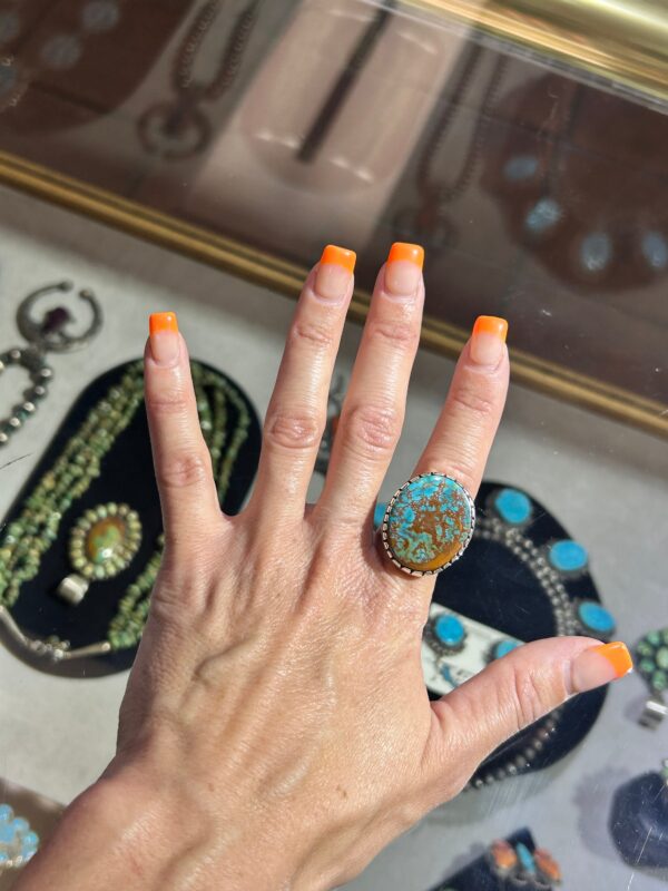 A hand holding an orange and turquoise ring.