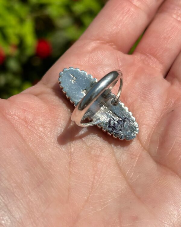 A silver ring with blue stones on the palm.