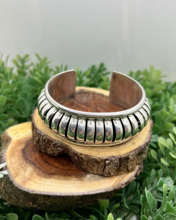 A silver cuff bracelet with a ribbed design.