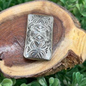 An ornate silver ring on top of a piece of wood.