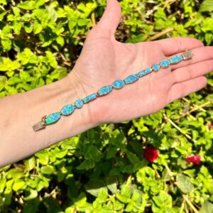 A person's hand holding a blue opal bracelet.