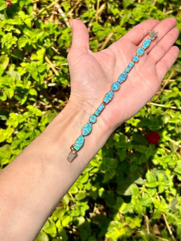 A person's hand holding a turquoise beaded bracelet.