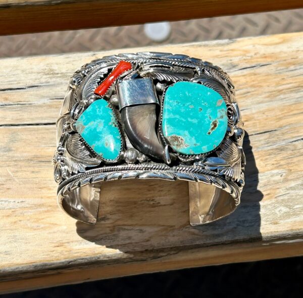 Silver cuff bracelet with turquoise stones and bear claw.