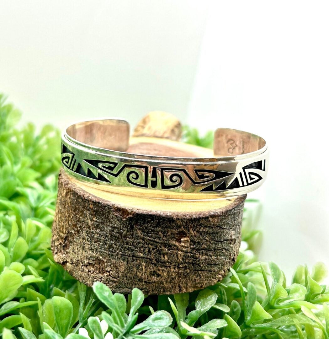 A silver cuff bracelet with a design on it.