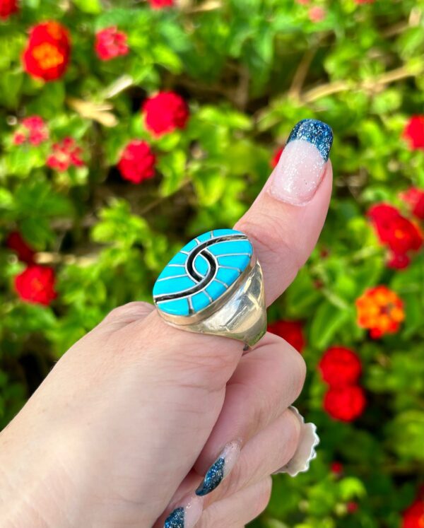 A turquoise and silver ring with a floral background.