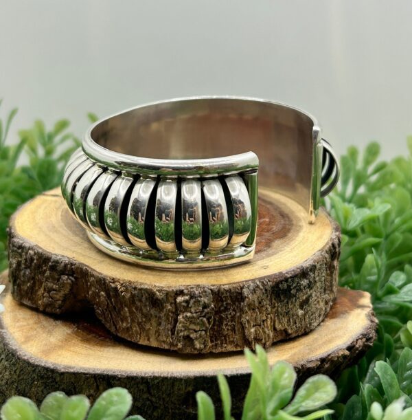 A silver cuff bracelet with a ribbed design.