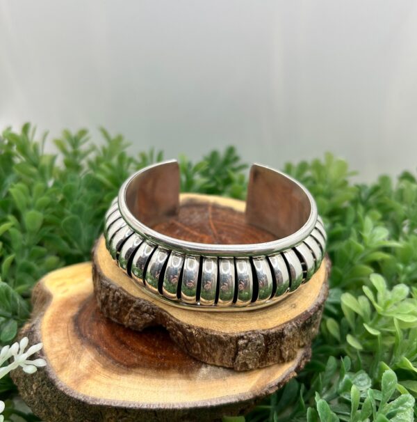 A silver cuff bracelet with a ribbed design.