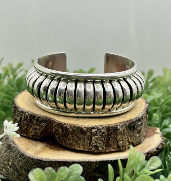 A silver cuff bracelet with a ribbed design.