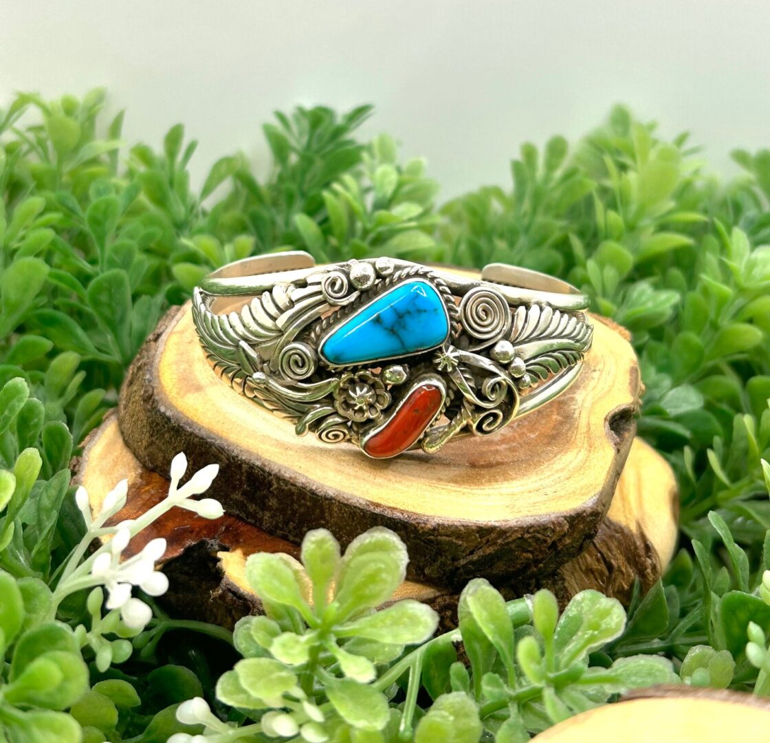 A silver and turquoise cuff bracelet on top of a piece of wood.