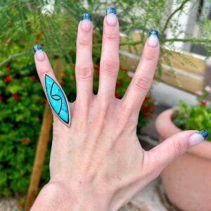 Hand with turquoise ring and glitter nails.