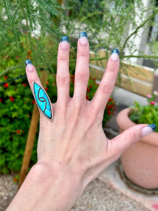 Hand with turquoise ring and glitter nails.