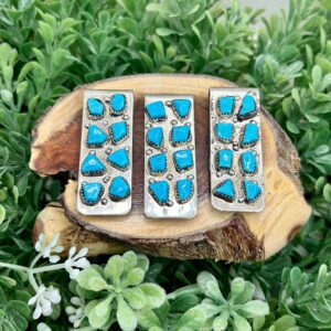 Three turquoise stone stud earrings on a piece of wood.