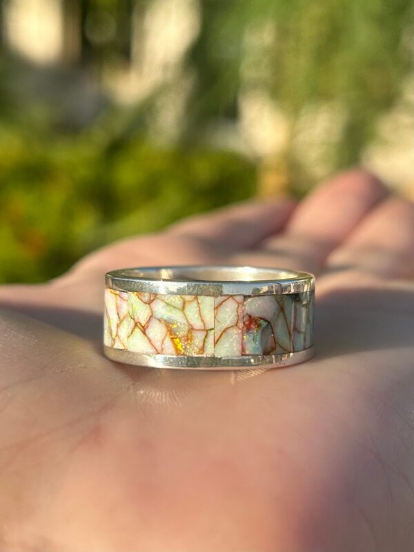 A silver ring with a colorful opal inlay.