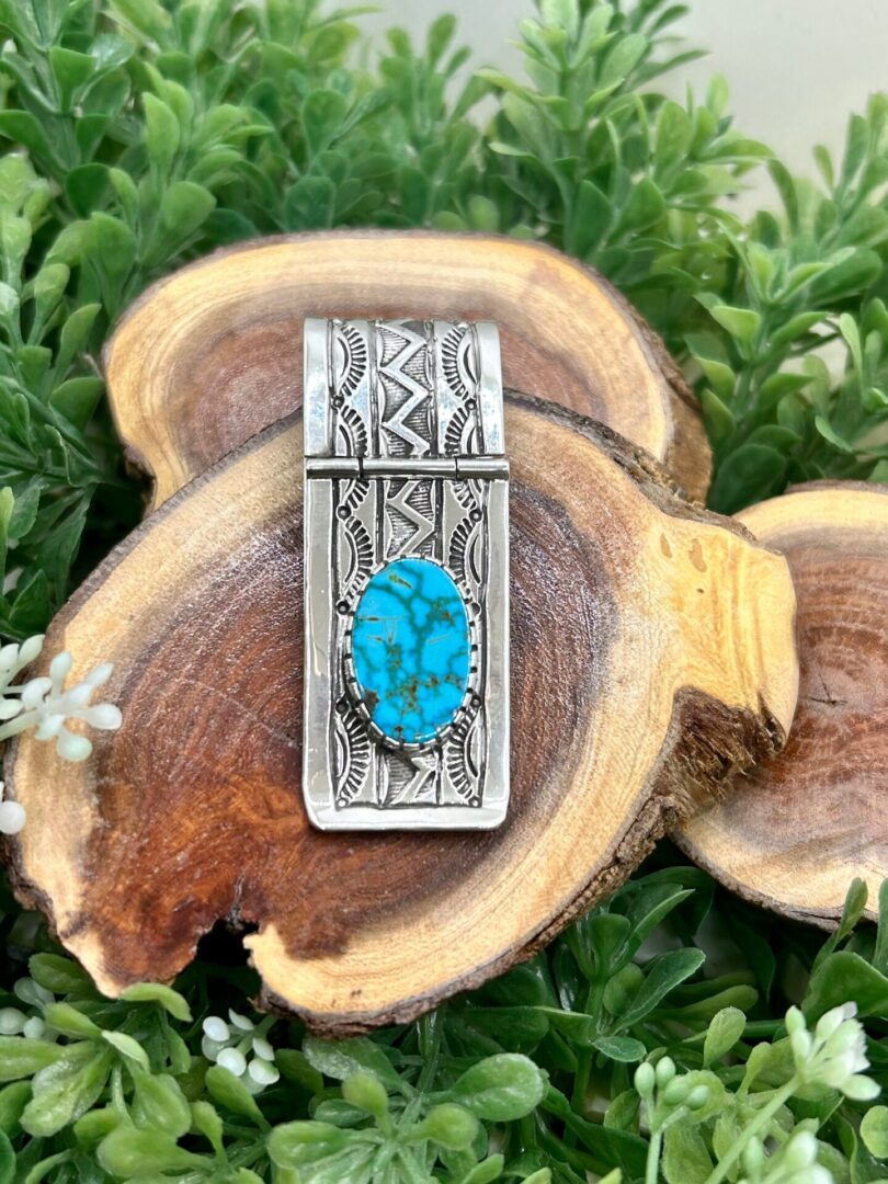 A silver money clip with a turquoise stone.