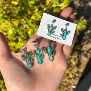A person holding a pair of turquoise cactus earrings and a card.
