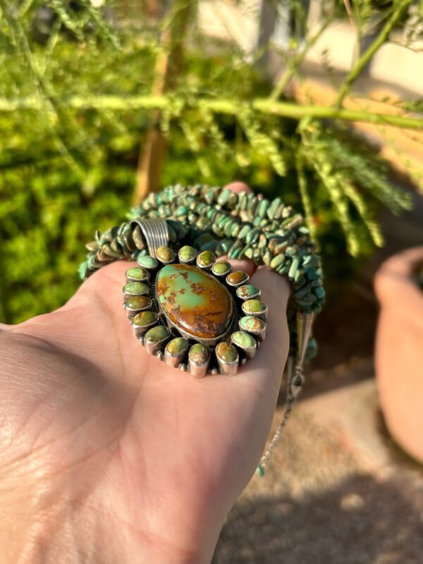 A hand holding a Native American-style turquoise necklace.