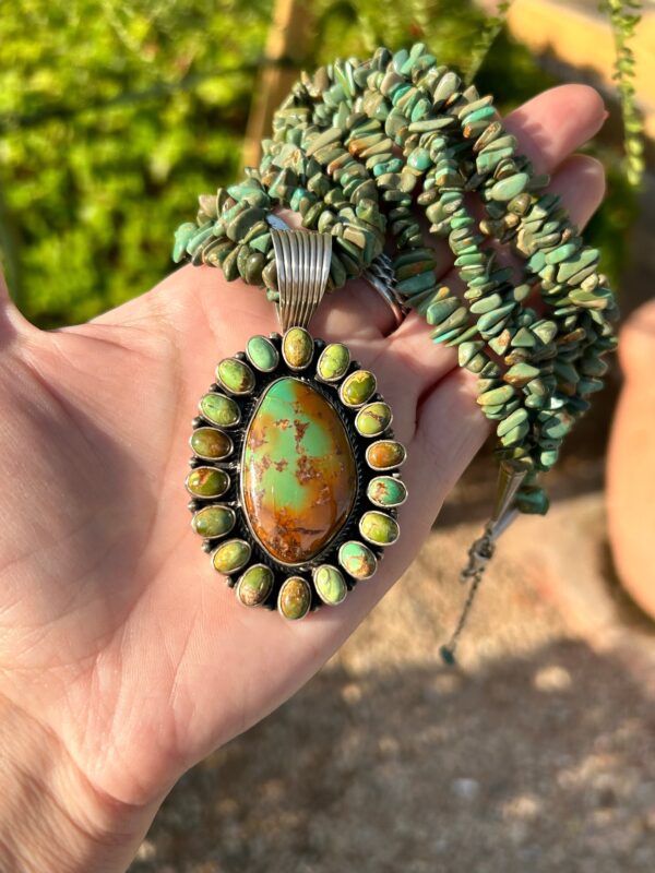 A hand holding a Native American-style turquoise necklace.