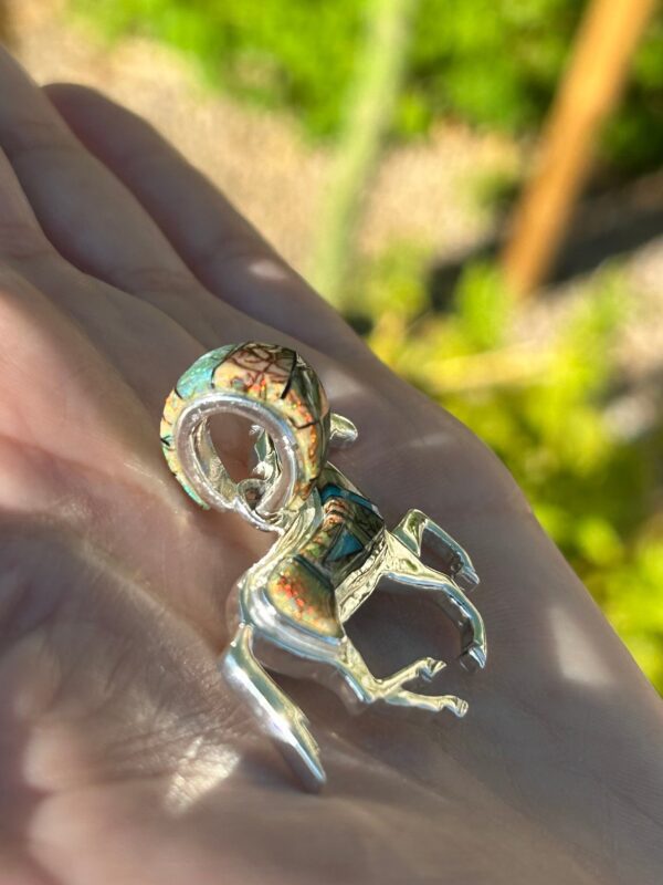 A silver ram charm with colorful inlays.