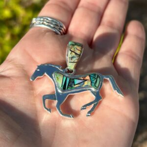 A silver horse pendant with colorful inlays.