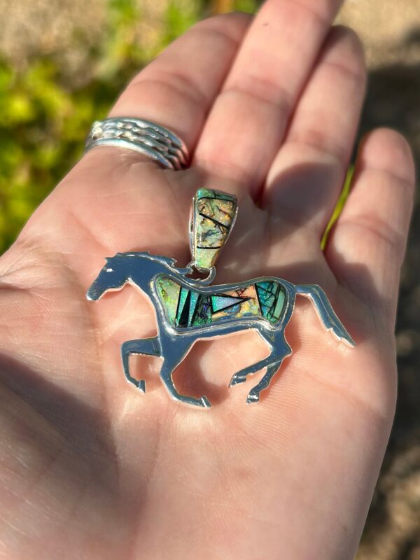 A silver horse pendant with colorful inlays.