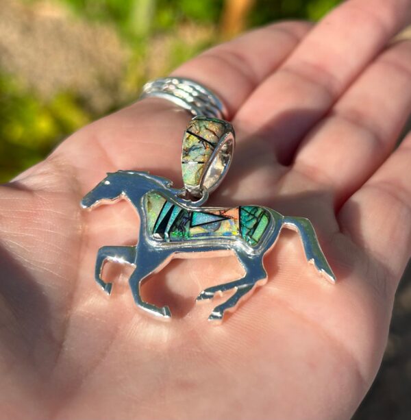 A silver horse pendant with colorful inlays.