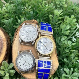 Three watches sitting on a piece of wood.