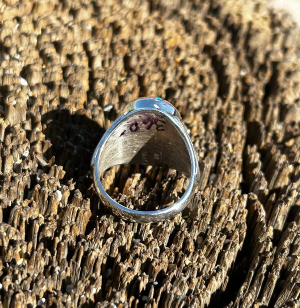 A silver ring with colorful gemstones on wood grain.