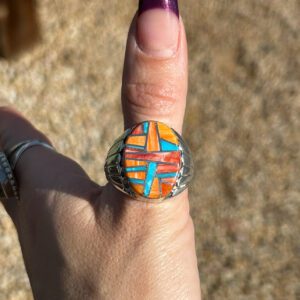 A person wearing a ring with colorful inlay.