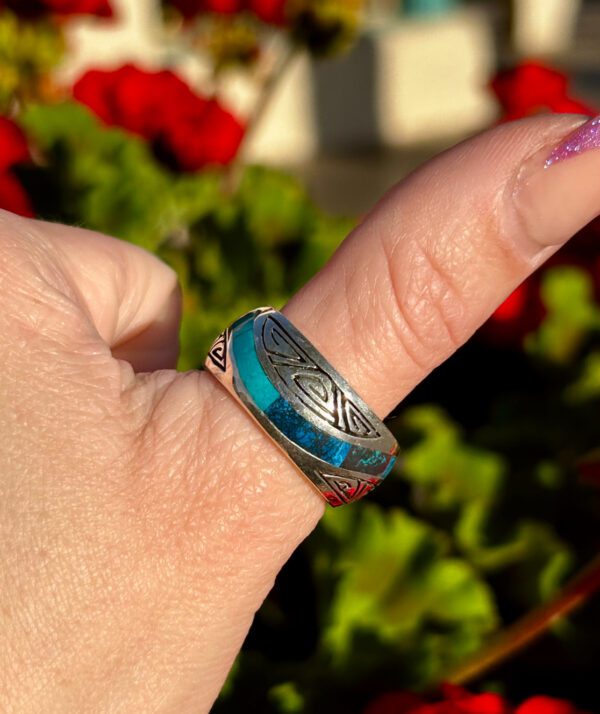 A silver ring with blue and green stones.